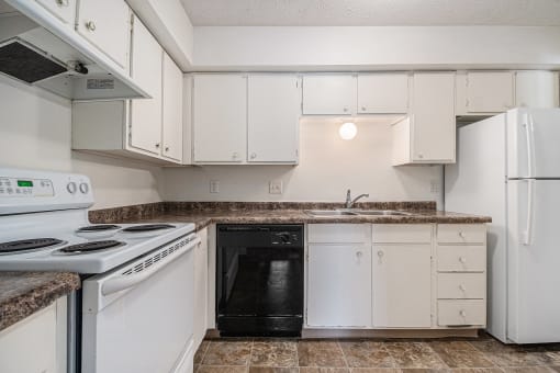 Omaha, NE Evergreen Terrace Apartments. A kitchen with white cabinets and black appliances