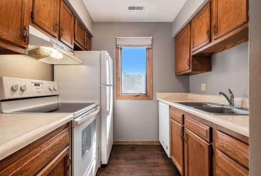 Omaha, NE Woodland Pines Apartments. A kitchen with white appliances and wooden cabinets
