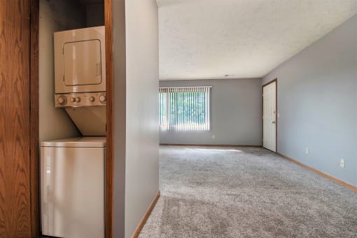 Omaha, NE Woodland Pines Apartments. A living room with a laundry closet with a washer and dryer in it.