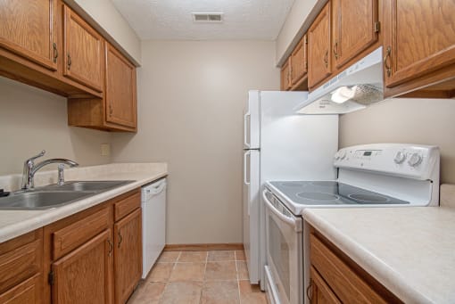 Omaha, NE Woodland Pines Apartments. A kitchen with wooden cabinets and white appliances