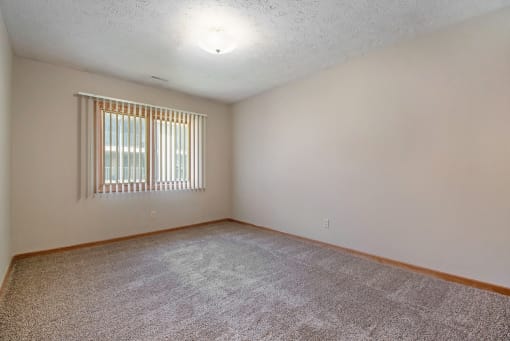 Omaha, NE Woodland Pines Apartments. A bedroom with a window and a carpeted floor