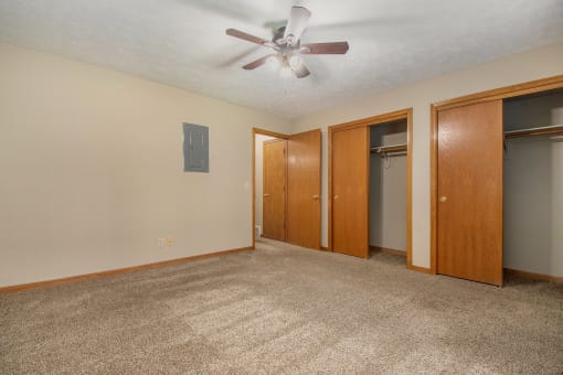 Omaha, NE Woodland Pines Apartments. A bedroom with a ceiling fan and two closets