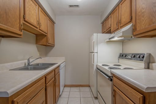 Omaha, NE Woodland Pines Apartments. A kitchen with wooden cabinets and white appliances