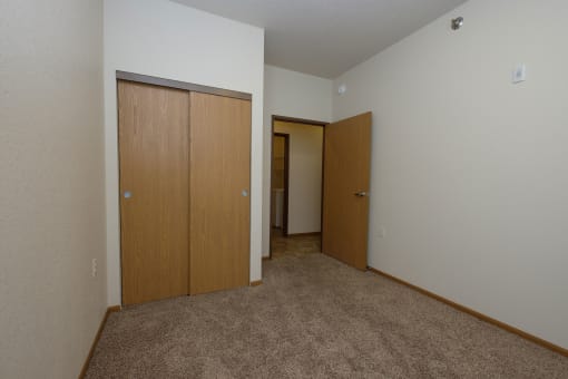 a bedroom with two doors and a hallway to a closet. Fargo, ND North Sky Apartments