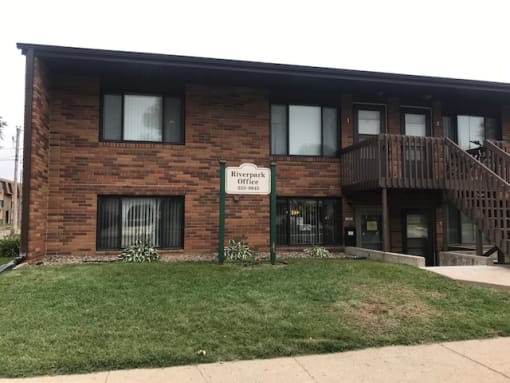 a brick building with a sign in front of it. Bismarck, ND Riverpark Apartments