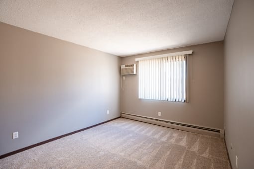 a bedroom of an empty house with a window. Roseville, MN Rosedale Estates Apartments