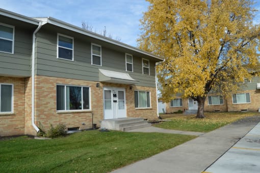 an apartment building with a sidewalk and a tree. Fargo, ND Sheyenne Terrace