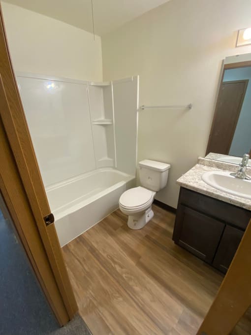 a bathroom with a toilet and a sink and a bath tub. Fargo, ND Sheyenne Terrace