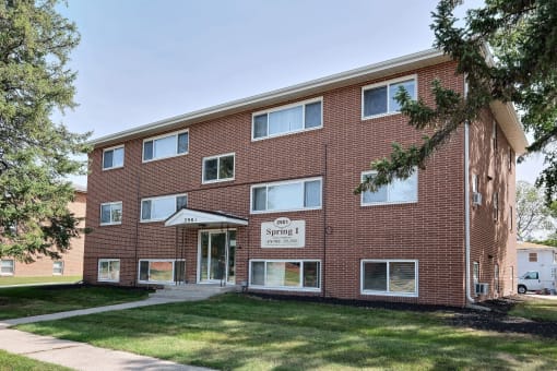 a brick building with a sidewalk in front of it. Fargo, ND Spring Apartments