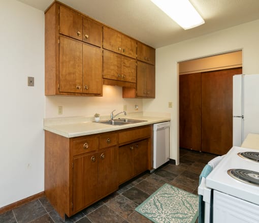 a kitchen with white appliances and wooden cabinets. Fargo, ND Islander Apartments