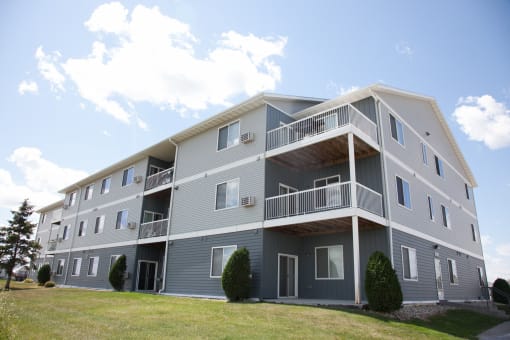 An exterior view of a gray apartment building with balconies. West Fargo, ND West Lake Apartments.