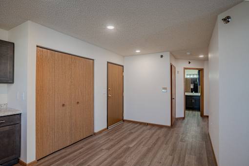 a long hallway with white walls and wooden floors and wooden doors. Fargo, ND Lake Crest Apartments