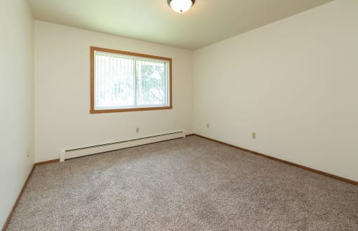 a bedroom with carpet and a window. Fargo, ND Islander Apartments