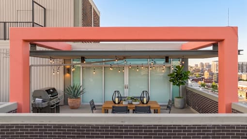 A patio with a table and chairs under a pink awning.