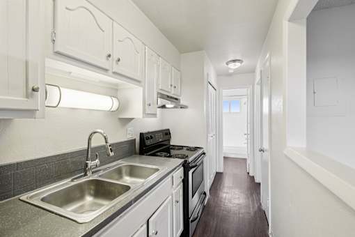 A kitchen with white cabinets and a stainless steel sink.