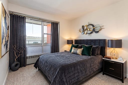 A bedroom with a large bed and a window with curtains.