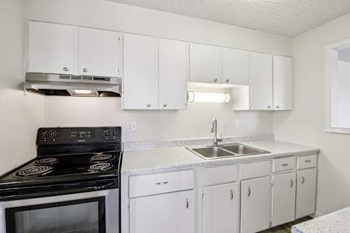 A kitchen with white cabinets and a black stove top oven.
