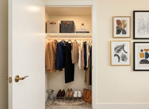 A closet with clothes and shoes on the floor.