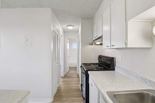 A kitchen with white cabinets and a black stove top oven.