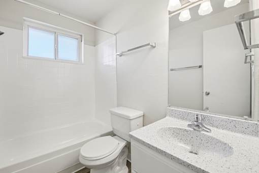 A white bathroom with a toilet, sink, and bathtub.