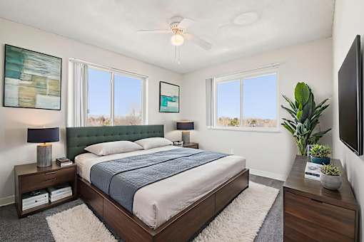 A bedroom with a bed, nightstand, and a ceiling fan.