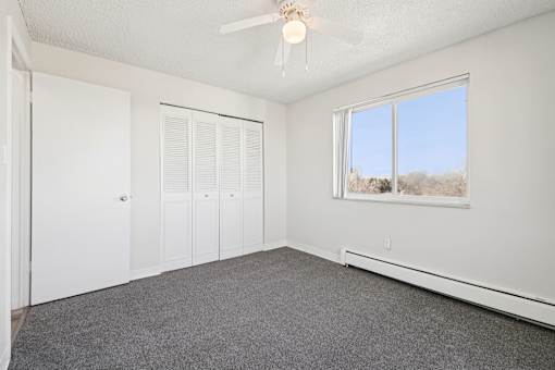 A room with a ceiling fan and a window overlooking a snowy landscape.