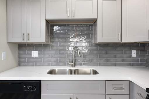 A kitchen with a black dishwasher and a stainless steel sink.