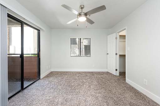 an empty living room with a ceiling fan and a glass door