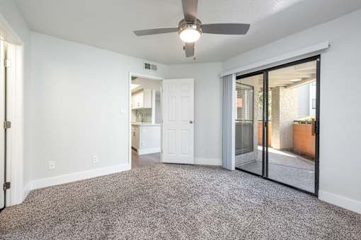 an empty living room with a ceiling fan and sliding glass doors to a patio
