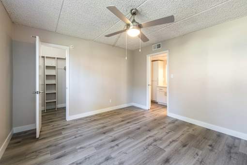 an empty living room with a ceiling fan and a closet