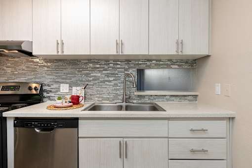 a kitchen with white cabinets and a stainless steel sink