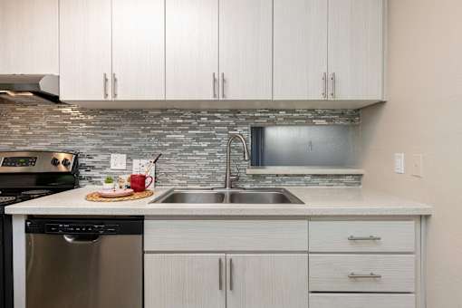 a kitchen with white cabinets and a stainless steel sink