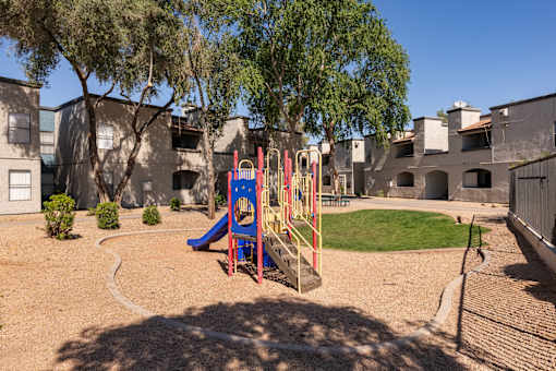 a playground with a swing set and slides in front of a building