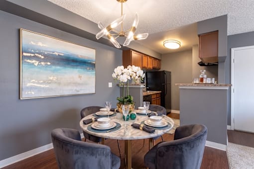 A dining room with a table set for two and a painting on the wall.
