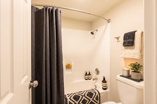 A bathroom with a white tub and a black and white patterned towel.