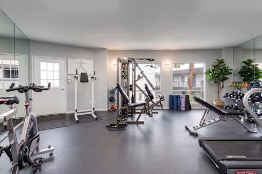 A spacious gym with a variety of equipment including treadmills, stationary bikes, and weight machines.