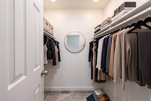 A hallway with a mirror and clothes hanging on the wall.