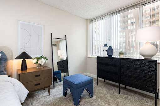 a bedroom with a large window and a bed with a blue ottoman