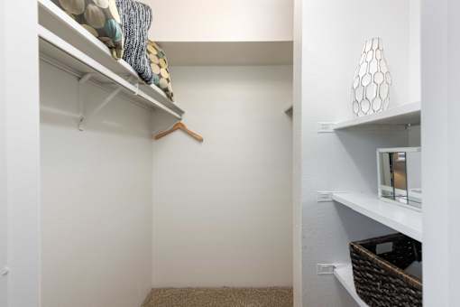 a walk in closet with shelves and a closet door with a mirror