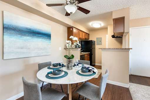 a dining area with a table and chairs and a ceiling fan