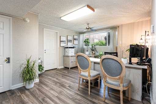 a living room with two chairs and a desk and a window