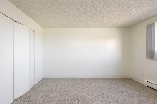 an empty room with white walls and a window and a closet