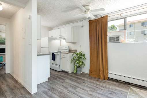 a small kitchen with a ceiling fan and a curtain