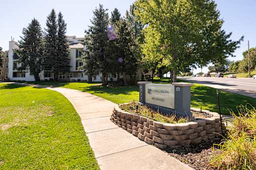 a sidewalk in front of a building with trees and grass