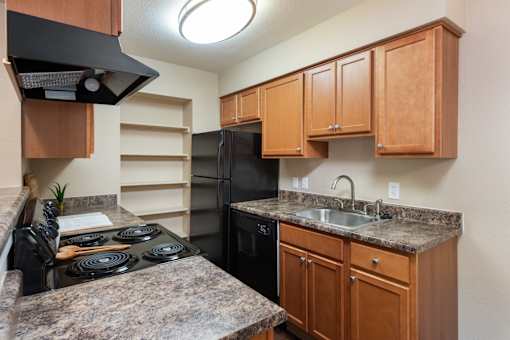 a kitchen with black appliances and granite counter tops and wooden cabinets