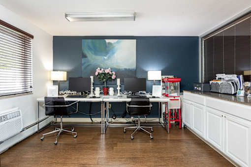 an office with desks and chairs and a painting on the wall