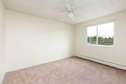an empty bedroom with a ceiling fan and a window