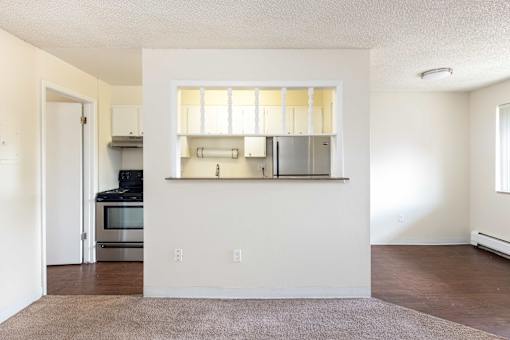 an empty living room and kitchen with a hard wood floor