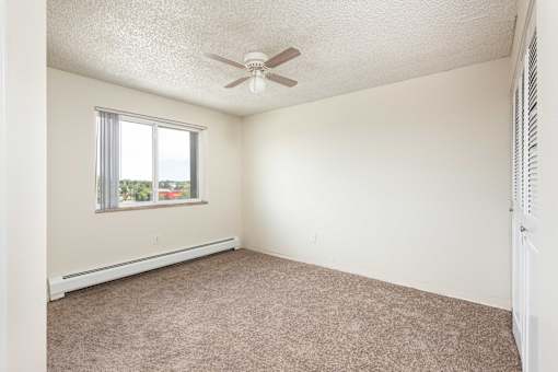 an empty bedroom with a ceiling fan and a window