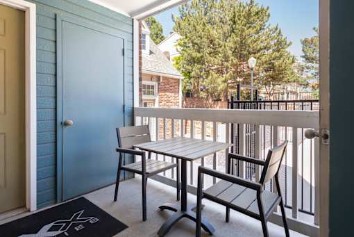a balcony with a table and chairs and a blue door